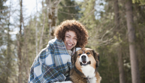 Frau kuschelt mit Hund in Winterlandschaft