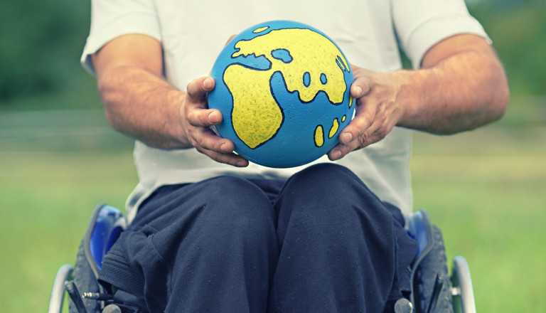 Rollstuhlfahrer mit Weltugel
